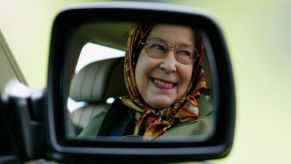 Queen Elizabeth II reflected in a mirror of a Land Rover as she competes in the Driving Grand Prix in Windsor, England