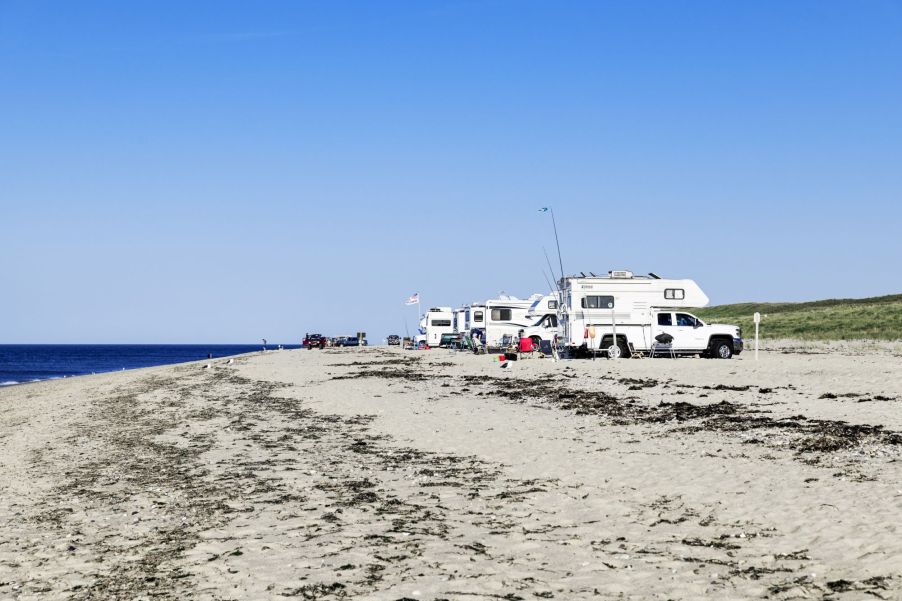 A few RVs camping on a beach.