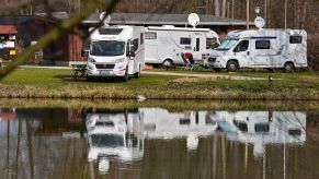 A few RVs at an RV camping site in front of a lake.