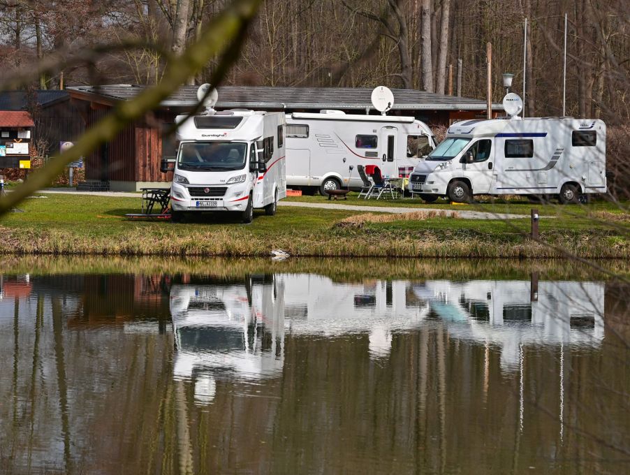 A few RVs at an RV camping site in front of a lake.