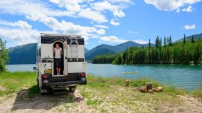 An RV parked in a mountainous area in front of a body of water.