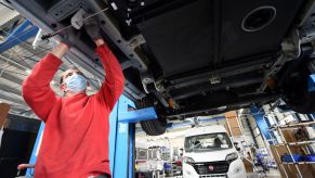 An auto worker installing a wastewater black tank into a RV motorhome/work van