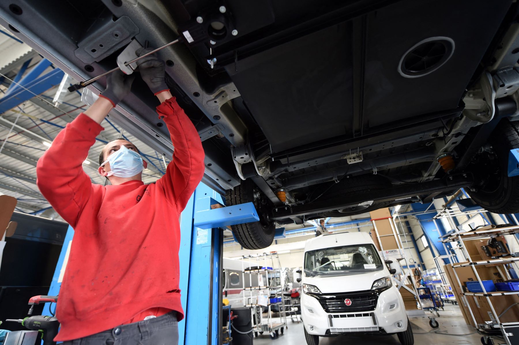 An auto worker installing a wastewater black tank into a RV motorhome/work van