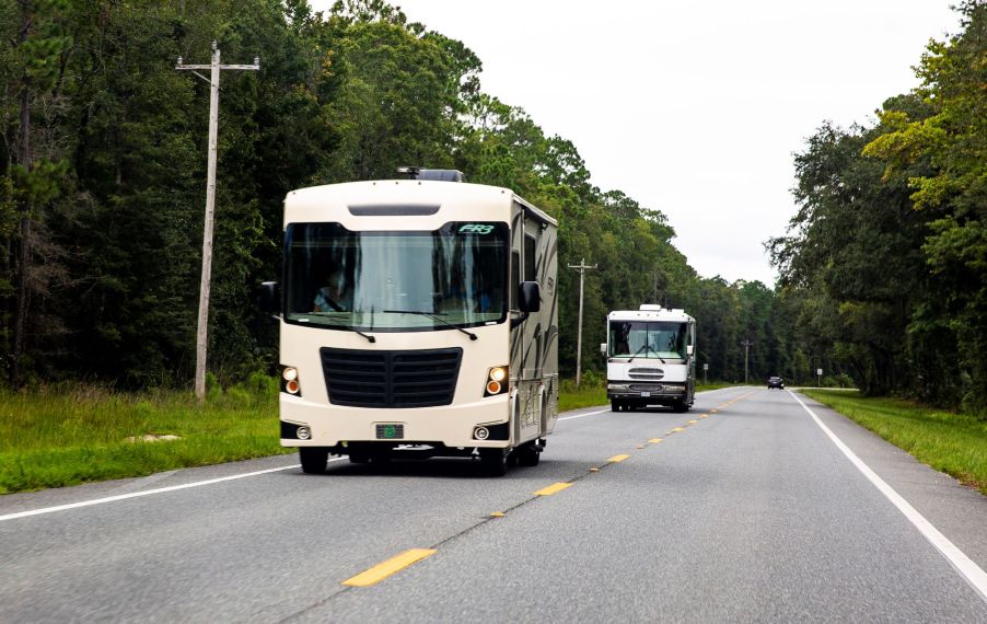 Two RVs driving down a road.