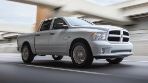 A white 2022 Ram 1500 Classic drives on an urban road.