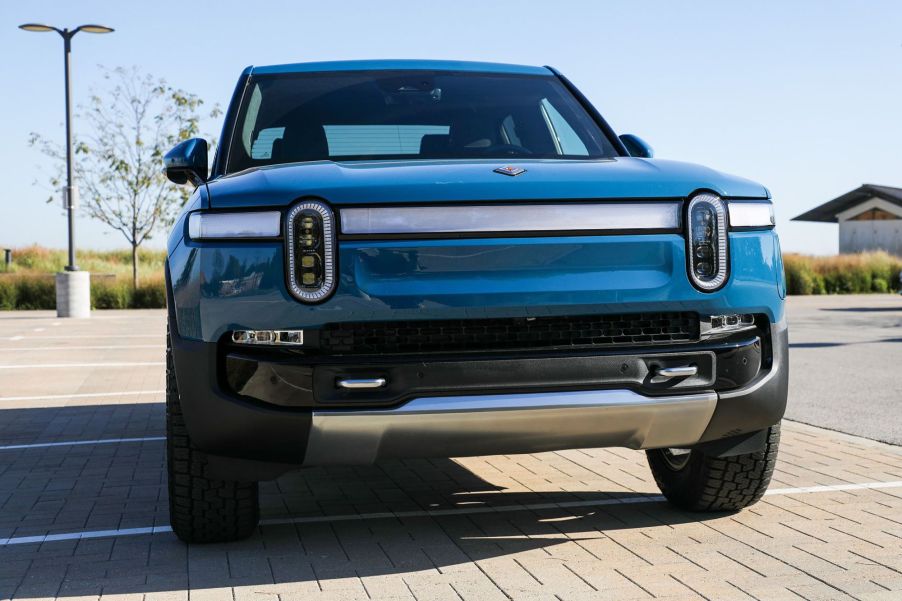 Blue Rivian parked on brick.