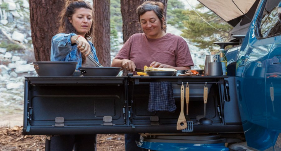 People are cooking using the 2022 Rivian R1T camp kitchen.