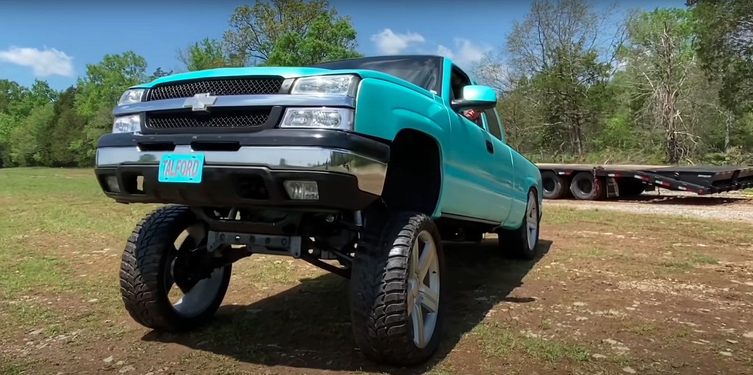 Silverado 1500 pickup truck with a dramatic "Carolina Squat" driving through a field.