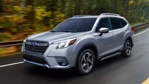 A gray 2022 Subaru Forester small SUV is driving on the road.