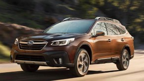 A brown 2022 Subaru Outback midsize SUV is driving on the road.