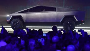 Tesla Cybertruck on a stage in front of a crowd of people with a blue haze.