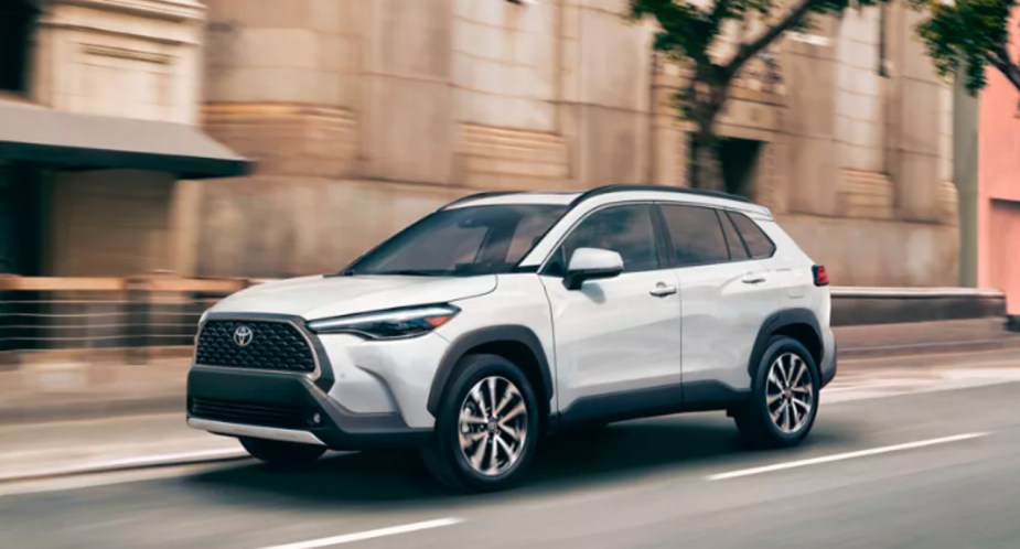 A white 2022 Toyota Corolla Cross is driving on the road.