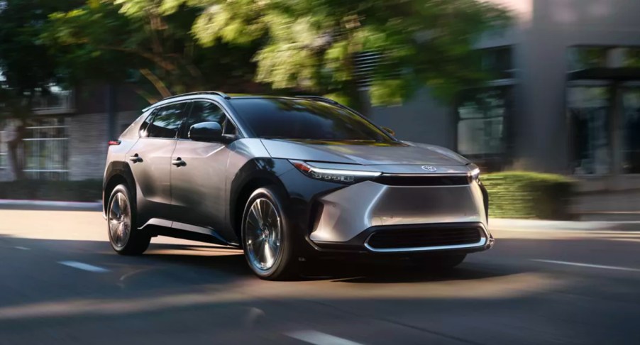 A gray 2023 Toyota bZ4X electric SUV is driving down the road.