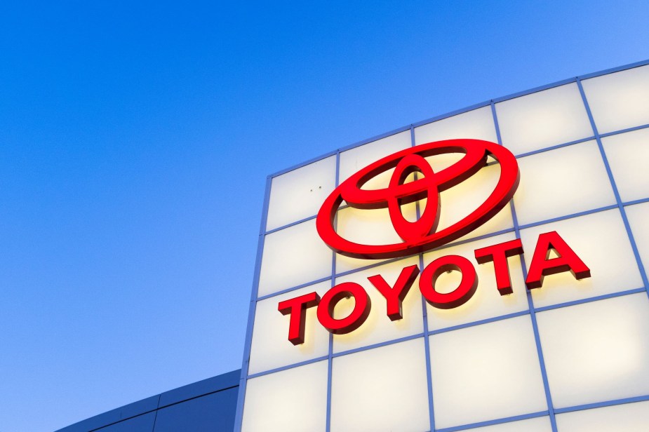 A red Toyota logo with Toyota written under it on a white background with a clear sky in the background. 