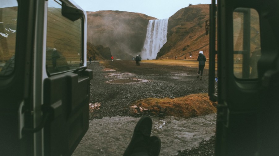 View of a waterfall through an open car door, highlighting secret car door drainage hole feature