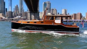 The Wheeler 38 restomod sailing through the bay of New York City, the Manhattan skyline in the background.