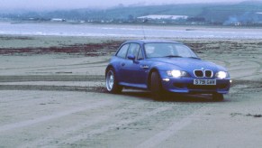 The discontinued BMW Z3 M Coupe is shown driving through sand.