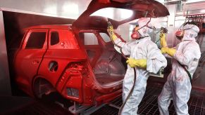 Workers at a BYD Automobile Company Limited factory plant in Xi'an, China, paint spraying a car frame body shell red