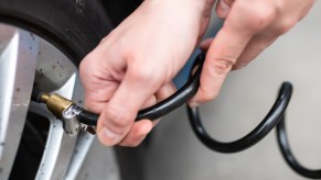 A woman checks the air pressure on a car tire at a gas station.