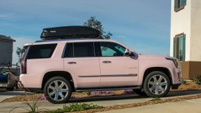 A pink Cadillac Escalade parked in a neighborhood. Free MLM cars like these can come with a lot of strings attached