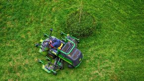 Birds-eye view of a green John Deer ride-on lawn mower in a field.