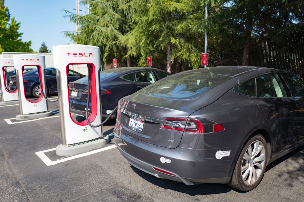 A line of Tesla cars charging at their stations. EV incentives can help reduce the cost of a Tesla