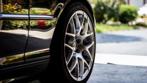 Black sedan with grey and silver wheels. A portable air compressor can quickly fill saggy tires.