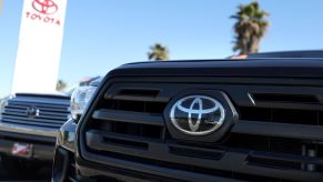 Close up of a Toyota logo on a truck's grille at a Toyota dealership, where you could go if your Toyota maintenance light is on