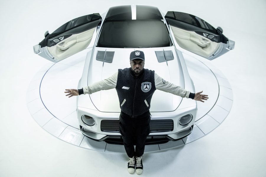 will.i.am in front of the white WILL.I.AMG Mercedes-AMG GT 4-Door concept with its rear-hinged doors open