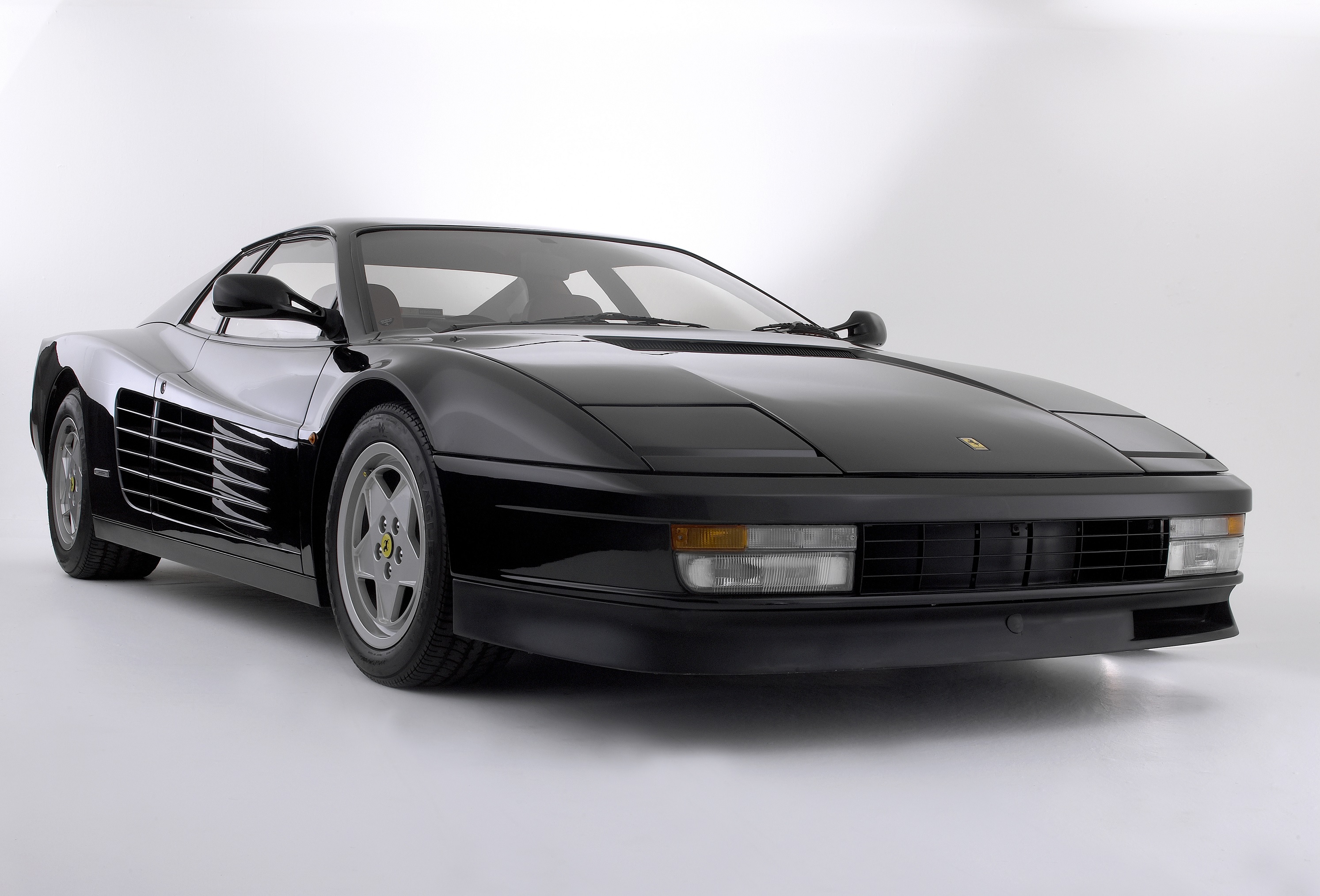 A black 1987 Ferrari Testarossa in a white studio