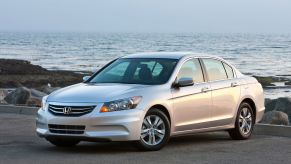 A silver-gray 2011 Honda Accord SE midsize sedan model parked by a beach