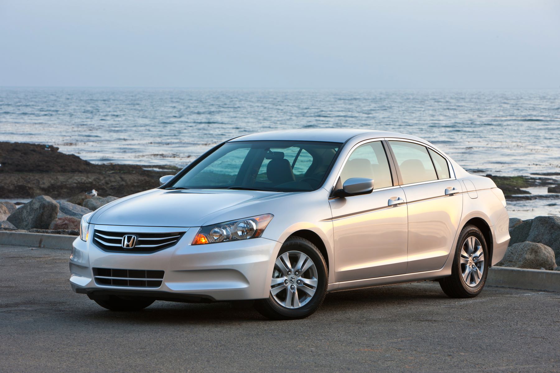 A silver-gray 2011 Honda Accord SE midsize sedan model parked by a beach