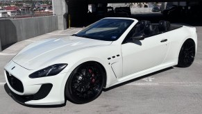 A white 2013 Maserati GranTurismo MC Convertible on black aftermarket wheels in a parking garage