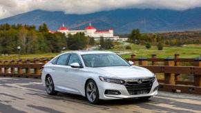 A white 2018 Honda Accord midsize sedan driving along a road