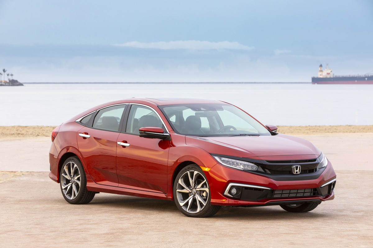 A red 2019 Honda Civic compact sedan parked next to a beach