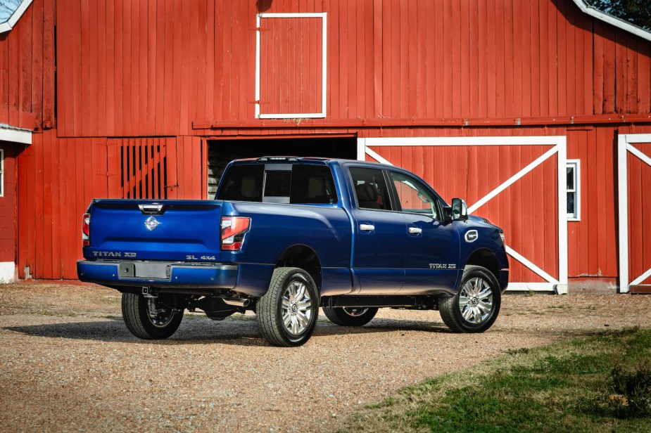 The rear end of a Nissan Titan XD medium duty truck, parked in a barnyard of a farm.