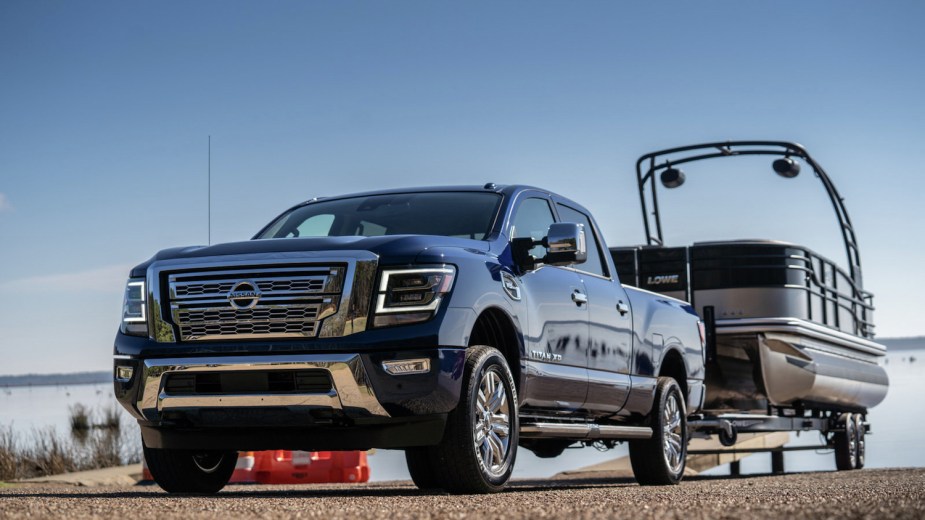 Promo photo of a Nissan Titan XD towing a pontoon boat up a boat ramp.