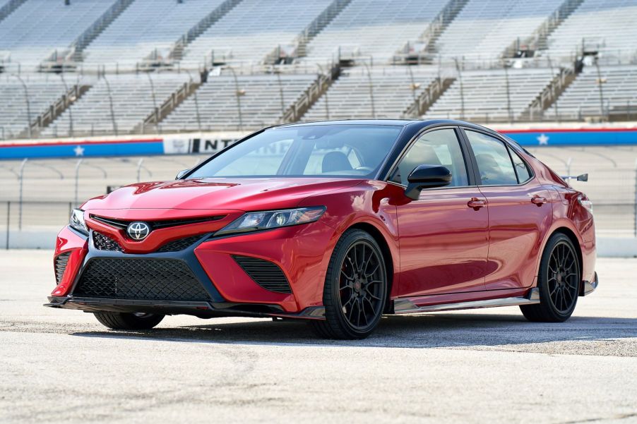 A 2020 Toyota Camry TRD midsize sedan model with the Supersonic Red color option parked on an empty race track