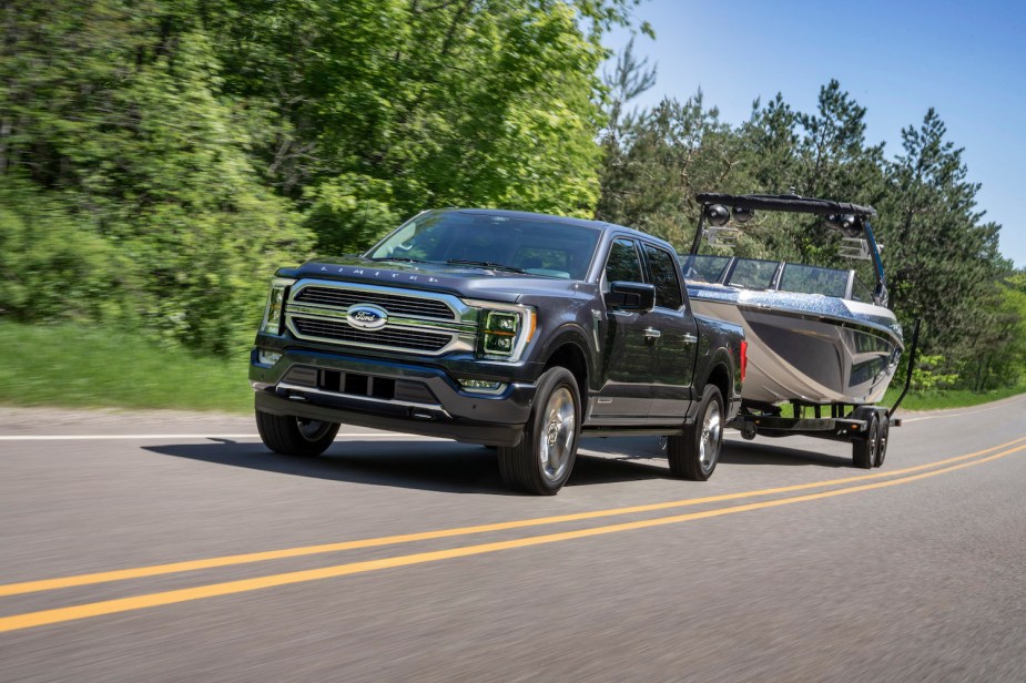 Ford F-150 pickup truck towing a boat down a two-lane, trees blurring by in the background.