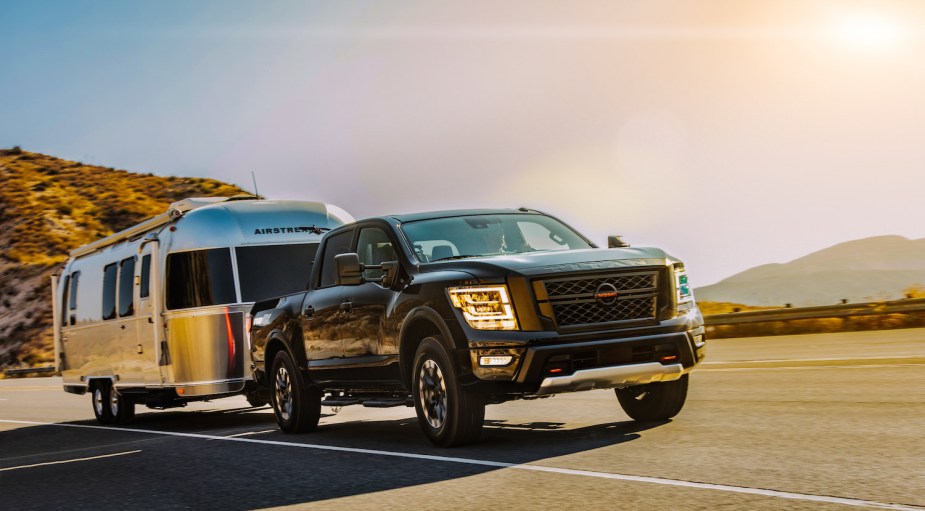 Closeup of a Nissan Titan pulling a camper trailer up a steep mountain road.