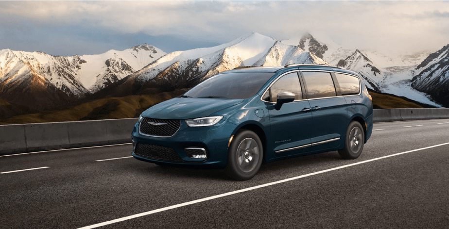 A 2022 Chrysler Pacifica Hybrid Pinnacle minivan with in Fathom Blue Pearl driving on a snowy mountain highway