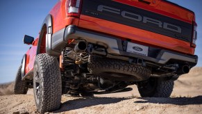 A red 2022 Ford F-150 Raptor traveling through a desert like area.