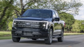 A black 2022 Ford F-150 Lightning Platinum driving down a road