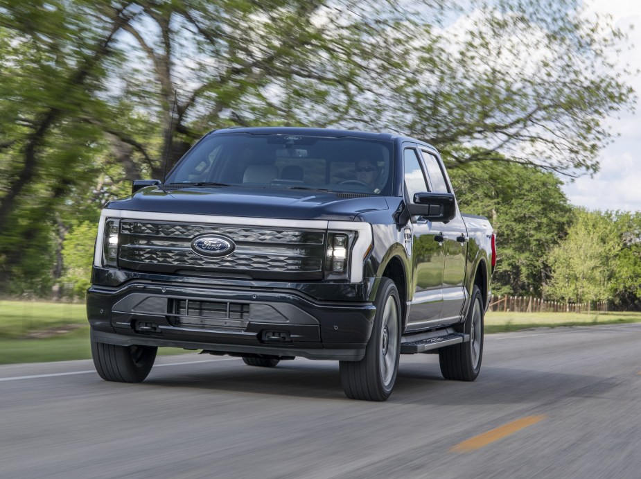 A black 2022 Ford F-150 Lightning Platinum driving down a road