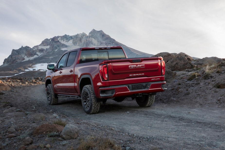 Red GMC pickup truck driving away on a dirt road.