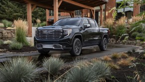 A promo shot of a black GMC Sierra pickup truck parked in a driveway.