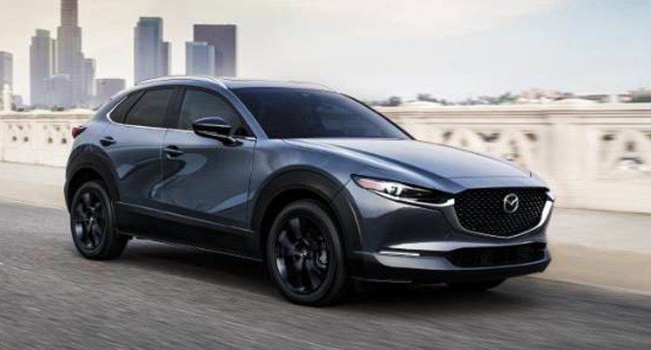 A gray 2022 Mazda CX-30 subcompact SUV is driving on the road. 