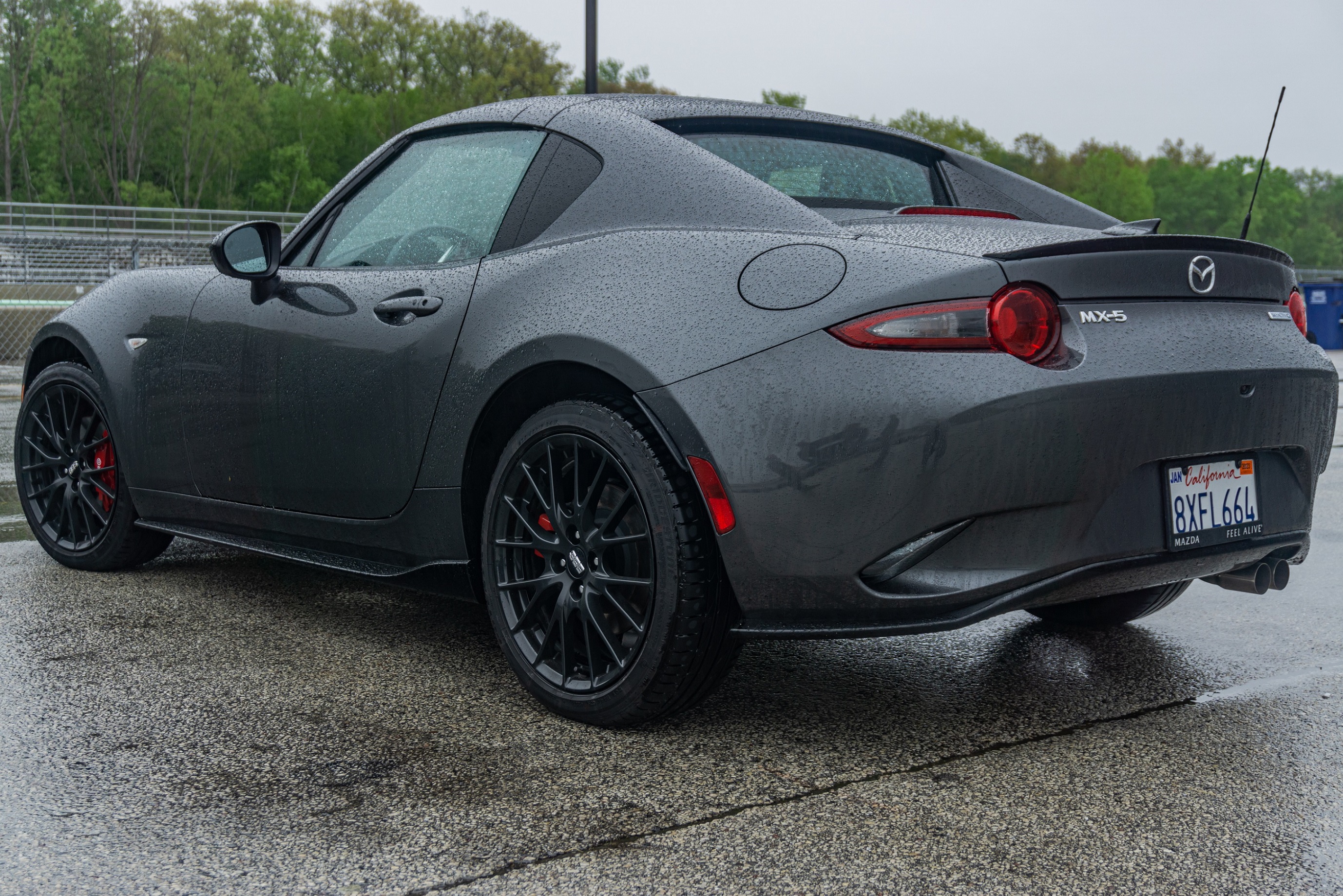 The rear 3/4 view of a gray 2022 Mazda MX-5 Miata RF Club at a racetrack parking lot