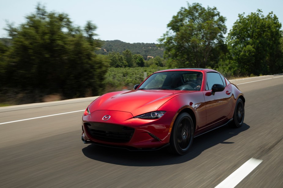 A red 2022 Mazda MX-5 Miata driving down a street