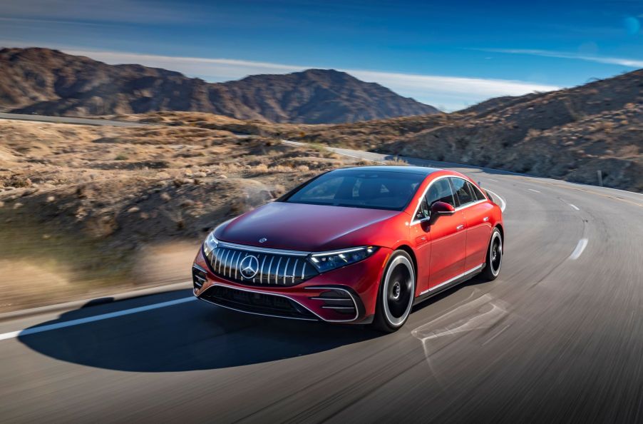 A red 2022 Mercedes-Benz AMG EQS all-electric (EV) sedan driving down a highway near hills